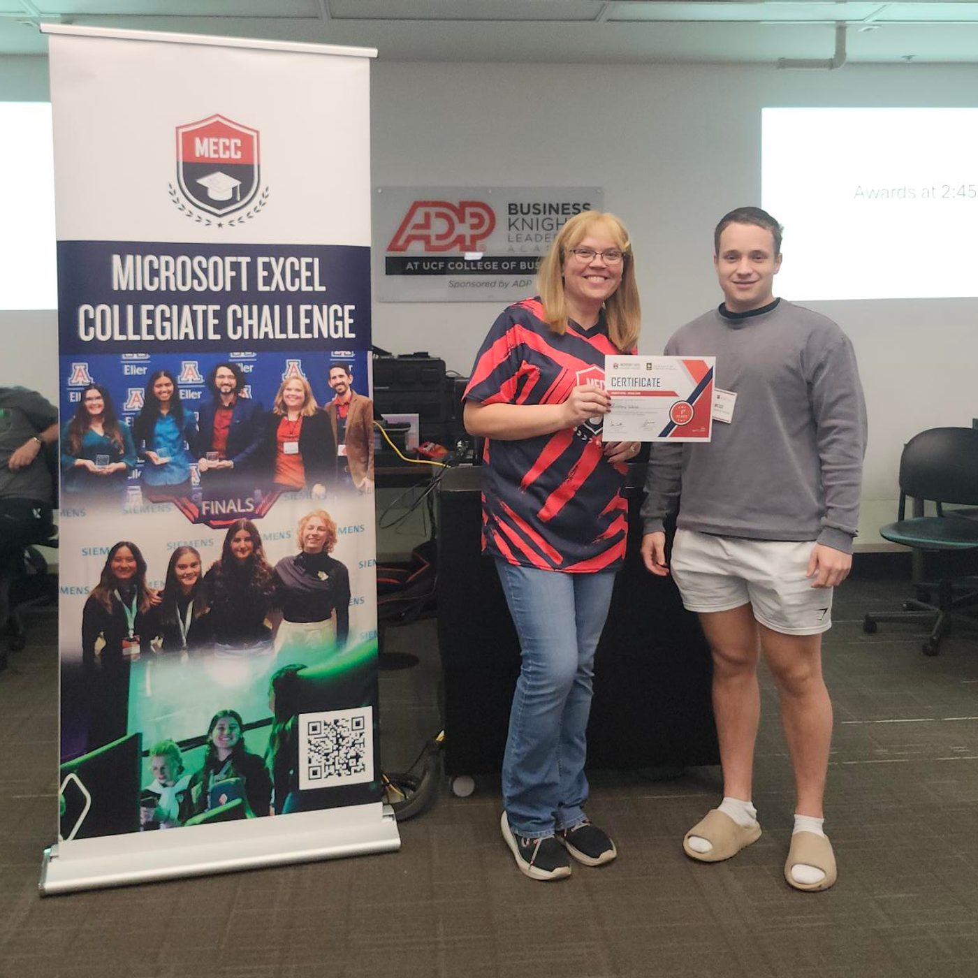 Zachary Weiss receiving the MECC Regionals certificate beside the Microsoft Excel Collegiate Challenge banner